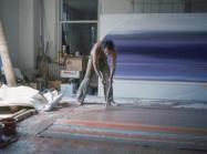 Ed Clark painting on the floor using a broom