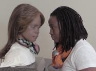 photo of a woman and a silicone clone of herself looking each other in the eye
