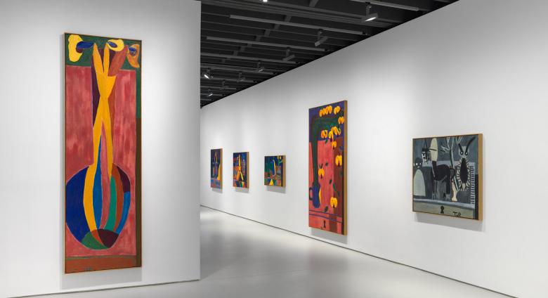 installation view, brightly colored tall paintings in a gallery with white walls