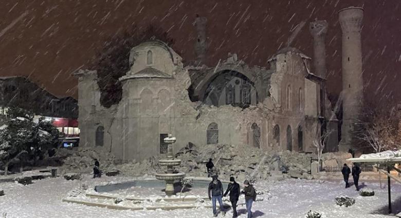 People walk next to a mosque destroyed by an earthquake in Malatya, Turkey, Monday, Feb. 6, 2023. A powerful quake has knocked down multiple buildings in southeast Turkey and Syria and many casualties are feared. (DIA images via AP)