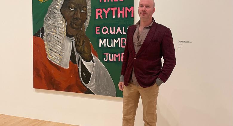 Jeffrey Magid standing in front of Henry Taylor's / was King When I Met the Queen, Syllable x Rythm Equals Mumbo Jumbo, 2013.
