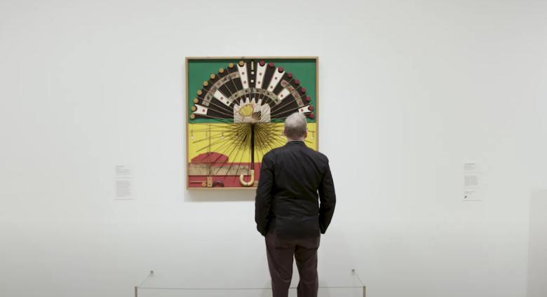 curator looking at noah purifoy work