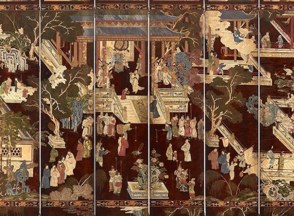 Folding screen, dark burgundy and intricately decorated to show a courtyard with Chinese structures and pavilions and garden features wit people mingling about.    
