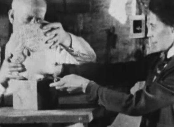 Two met workers from the 1920s adjust the head of a sculpture